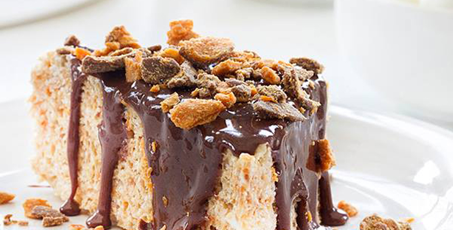 Butterfinger Cereal Treat with chocolate topping and ingredients scattered around it